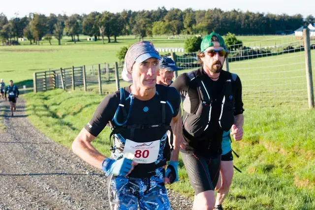 A group of men are running down a dirt road.