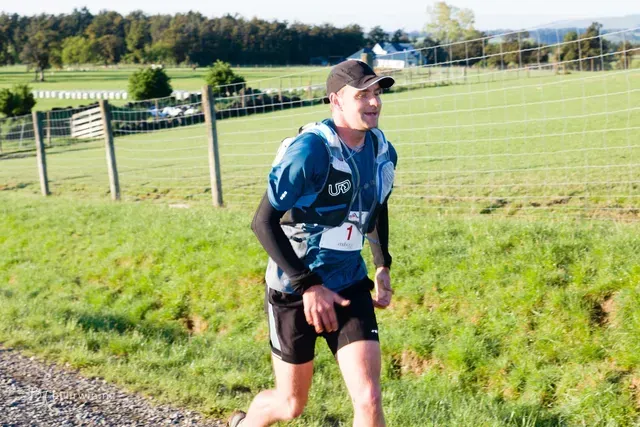 A man is running on a dirt road in a field.