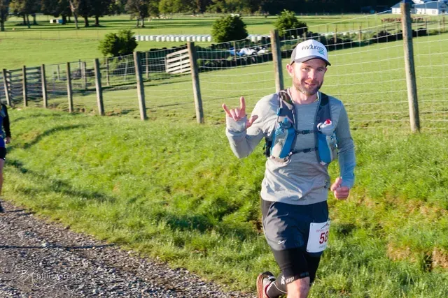 A man is running on a dirt road in a field.