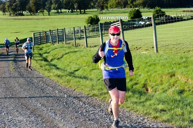 A group of people are running down a dirt road.