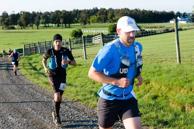A group of men are running down a dirt road.