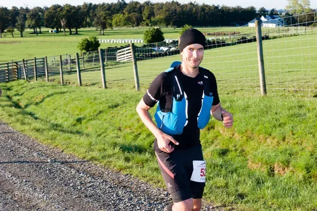 A man is running down a dirt road with the number 5 on his shorts