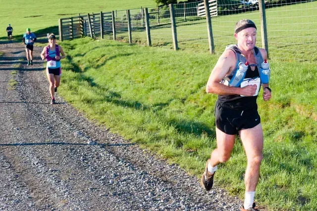 A group of people are running down a dirt road.