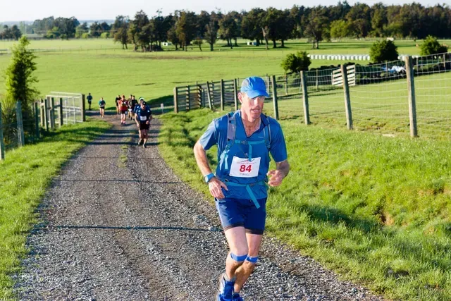 A man wearing a number 24 shirt is running down a dirt road.