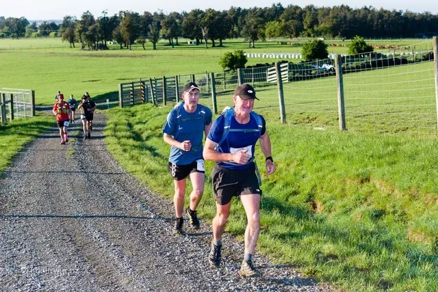 A group of people are running down a dirt road.