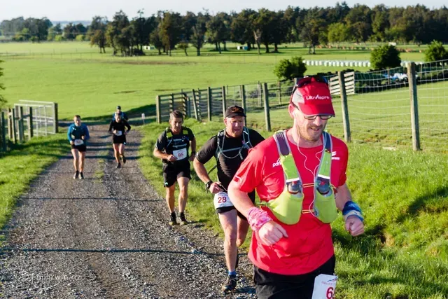A group of people are running down a dirt road.