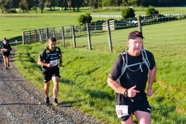 A group of people are running down a dirt road.