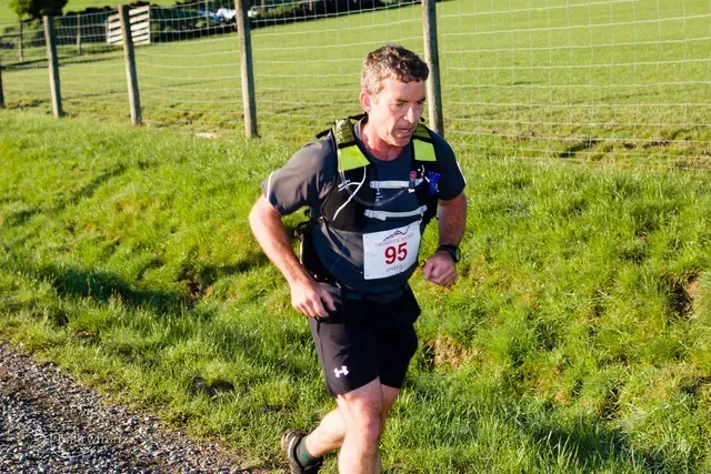 A man is running on a dirt road in a field.