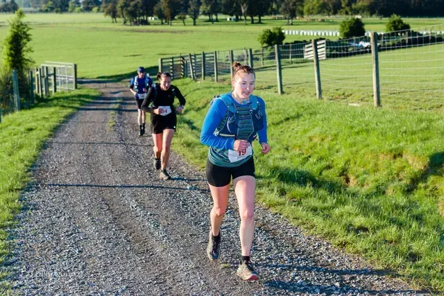 A group of people are running down a dirt road.