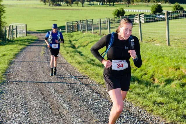 A man and a woman are running down a dirt road.