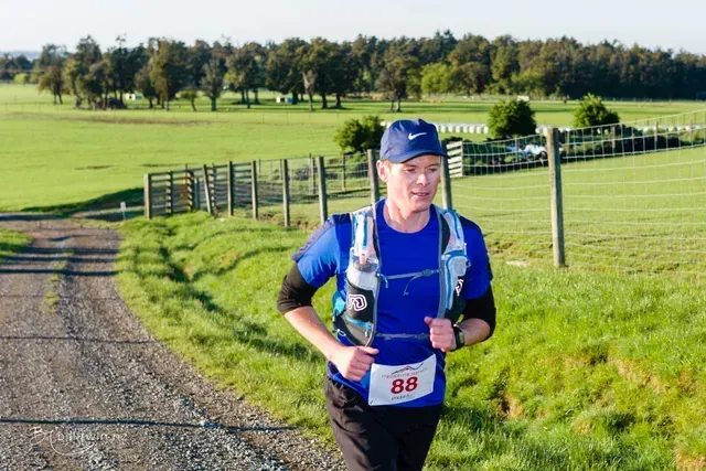 A man is running down a dirt road in a field.