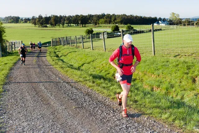A group of people are running down a dirt road.