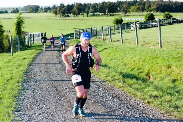 A group of people are running down a dirt road.