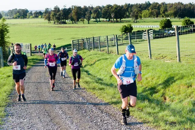 A group of people are running down a dirt road.