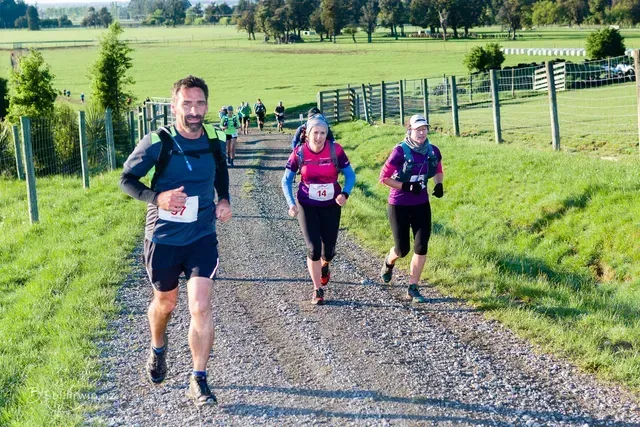 A group of people are running down a dirt road.