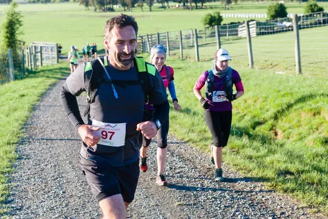 A group of people are running down a dirt road.