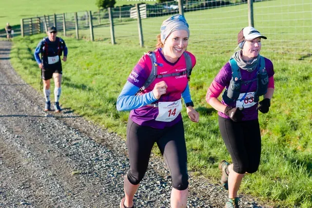 A group of people are running on a dirt road.
