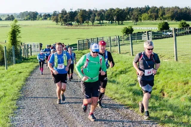 A group of people are running down a dirt road.