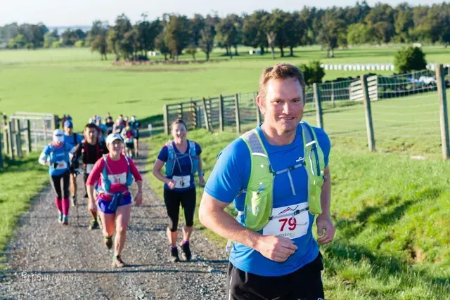 A group of people are running down a dirt road.