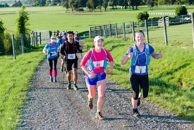 A group of people are running down a dirt road.