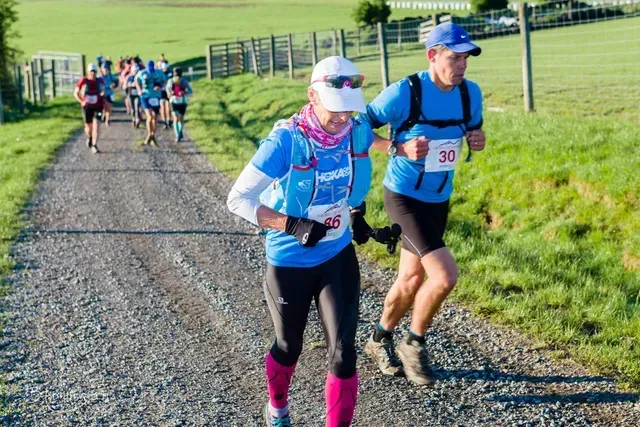 A group of people are running down a dirt road.