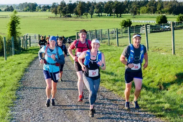A group of people are running down a dirt road.