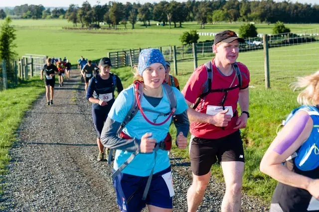 A group of people are running down a dirt road