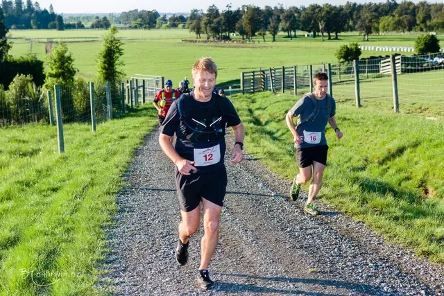 A group of men are running down a dirt road.