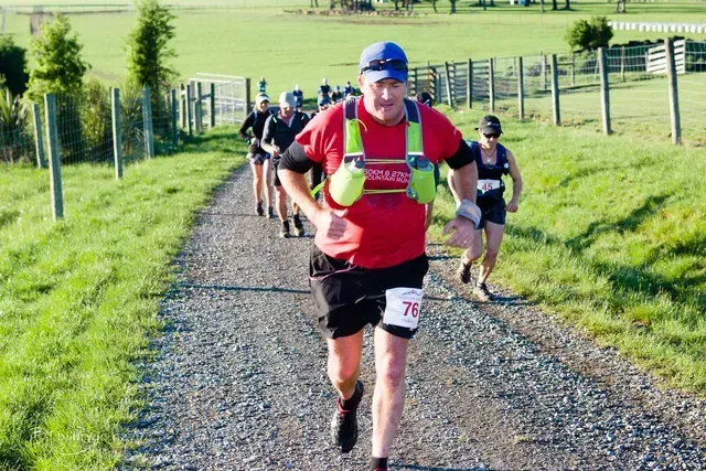A group of people are running down a dirt road.