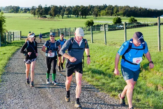 A group of people are running down a dirt road.