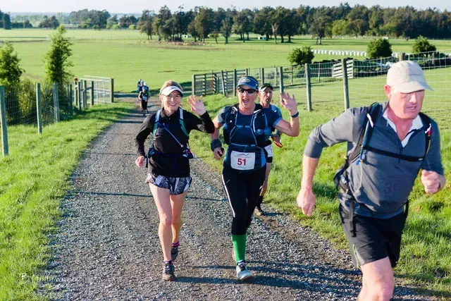 A group of people are running down a dirt road.