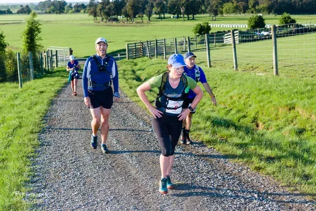 A group of people are walking down a dirt road.