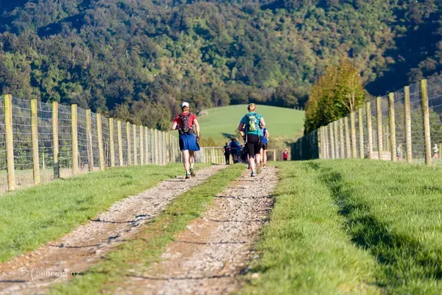 A group of people are running down a dirt road.