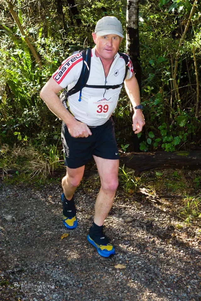 A man with the number 39 on his shirt is running in the woods.