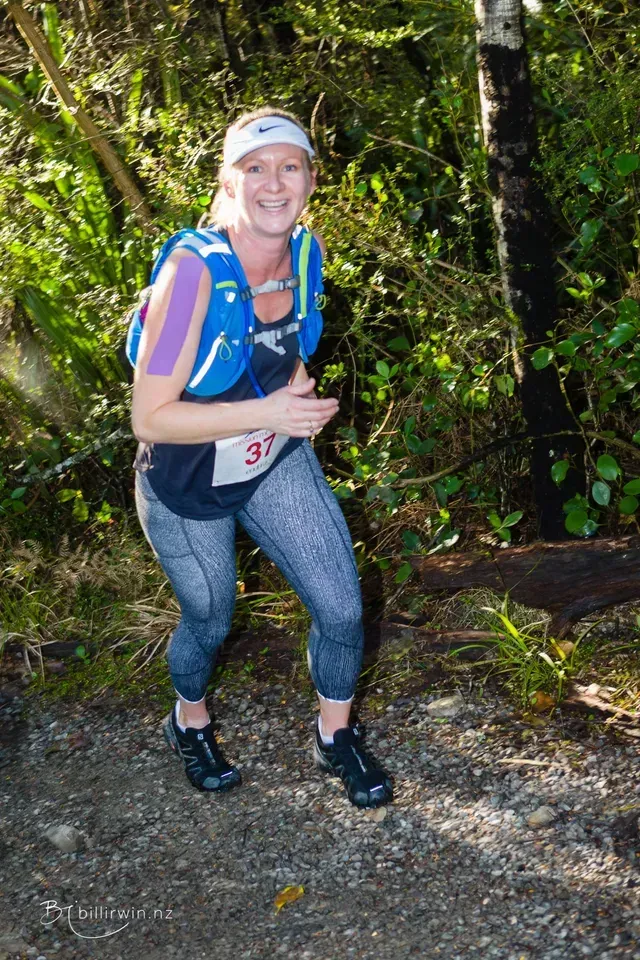 A woman is running on a trail in the woods.
