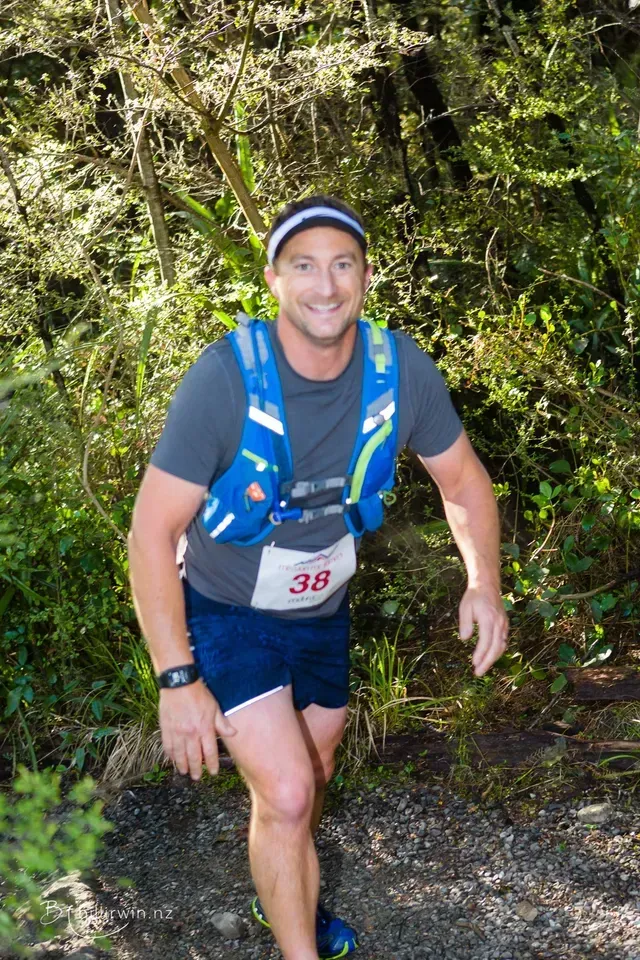 A man is walking down a trail in the woods.