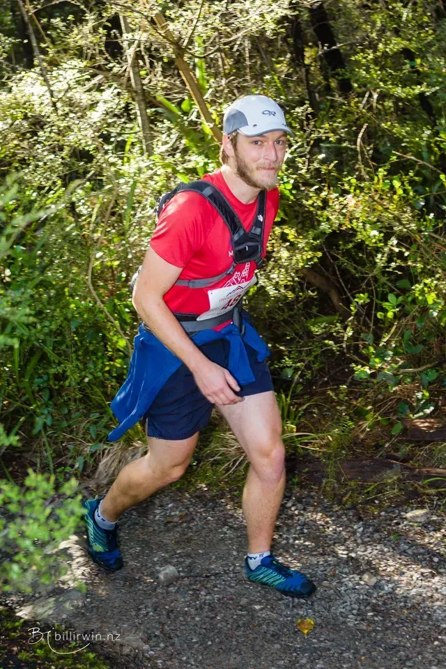 A man is running on a trail in the woods.