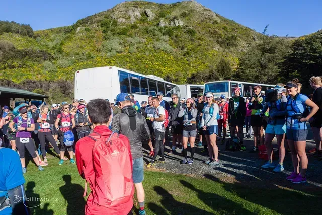 A group of people are standing in a field in front of a mountain.