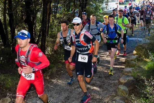 A group of men are running on a trail in the woods.