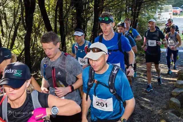A group of people are walking down a path in the woods.