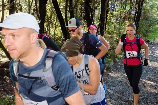 A group of people are walking down a path in the woods.