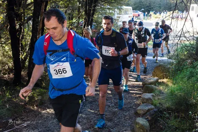 A group of people are running down a path in the woods.