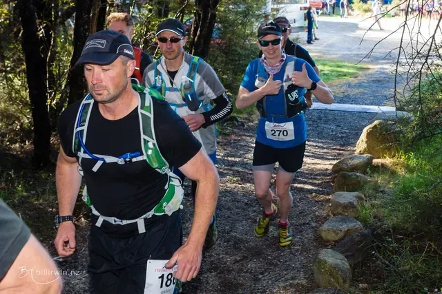 A group of people are walking down a path in the woods.
