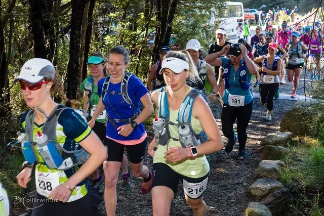 A group of women are running a race in the woods.