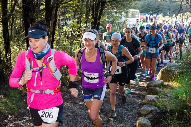 A group of people are running a trail in the woods.