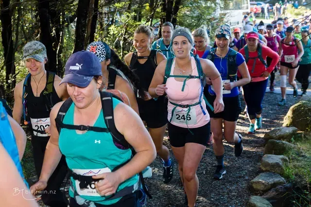 A group of women are running down a trail.
