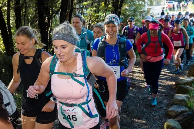 A group of women are running a race in the woods.