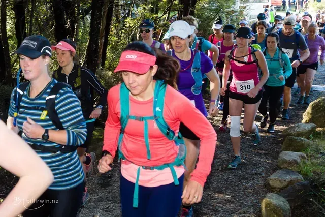 A group of people are running down a trail.
