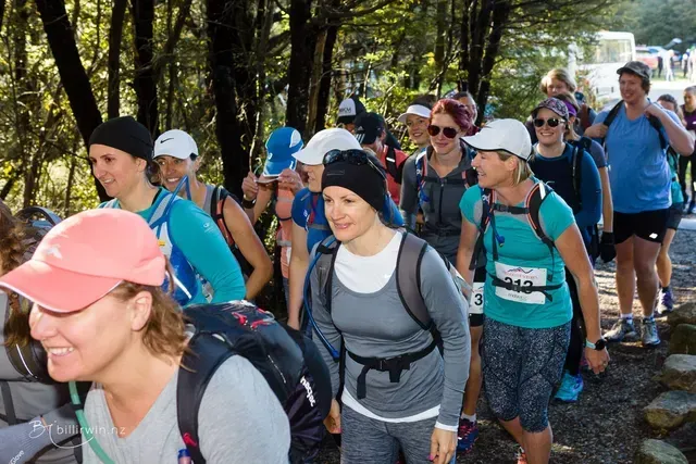 A group of women are walking down a path in the woods.