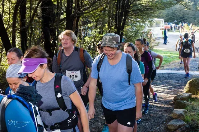 A group of people are walking down a path in the woods.